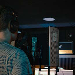 Hombre canta a micrófono en estudio de grabación